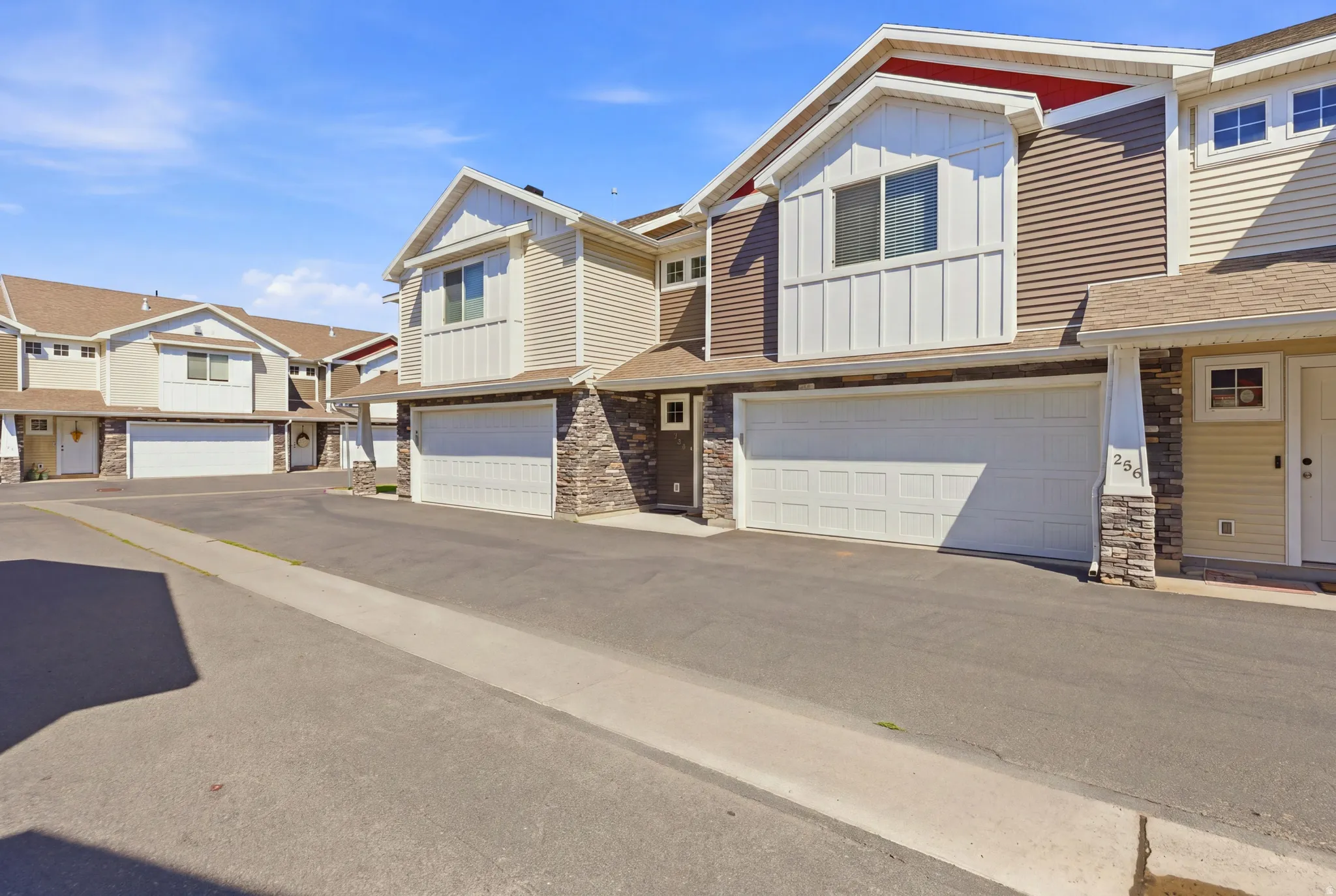 Multi-unit property featuring textured siding, stone facade accents, and attached garages