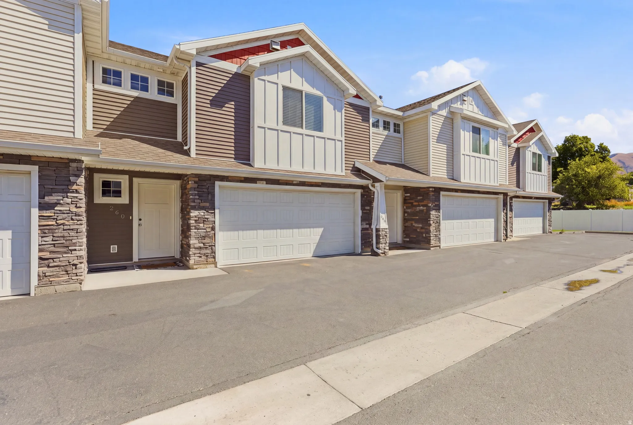 Multi-level exterior with mixed siding, stone veneer accents, and multiple attached garages