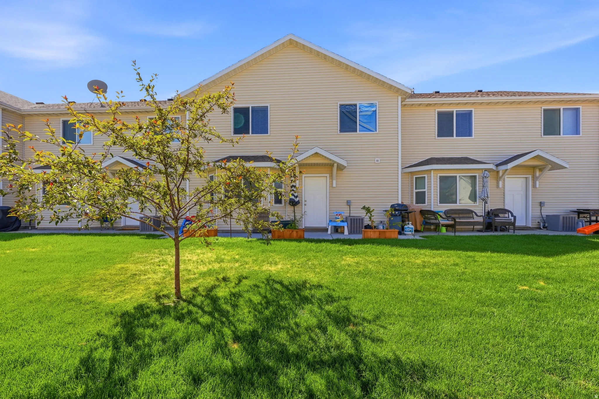 Expansive green lawn, mature tree, multi-pane windows, bay window, and covered entryways