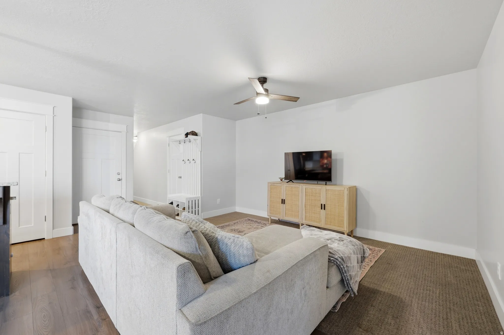 Recessed lighting, wood-finish flooring, built-in mudroom bench with coat hooks, ceiling fan, and white trim