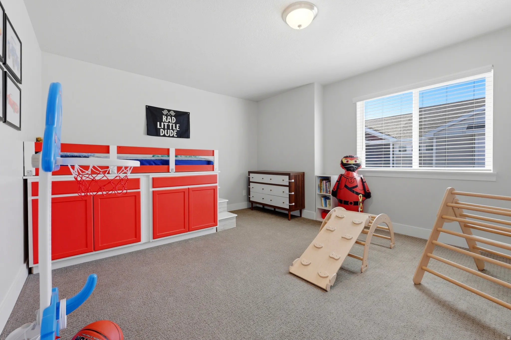 Light gray wall paint, carpet flooring, a window with horizontal blinds, and a flush mount ceiling light