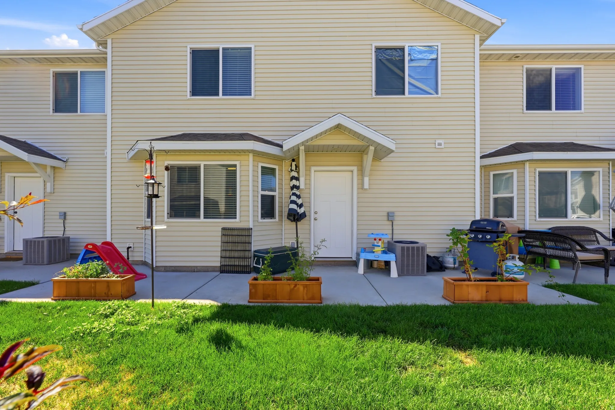 Private concrete patio with direct exterior access, wood planter boxes, and a manicured lawn