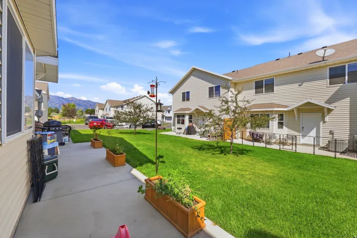 Expansive green lawn with mountain backdrop, concrete patio, and built-in planter boxes