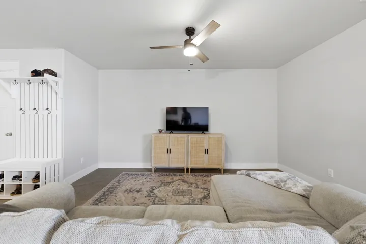 Recessed lighting, ceiling fan with light fixture, light gray walls, built-in mudroom bench with coat hooks, and dark flooring