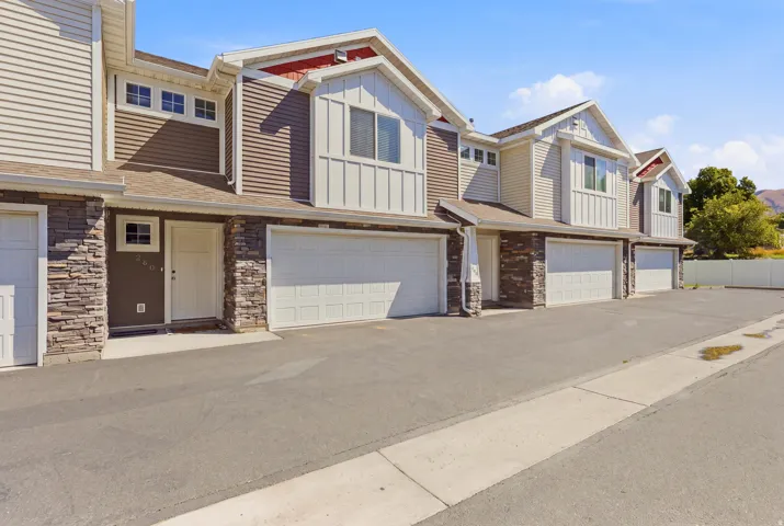 Multi-level exterior with mixed siding, stone veneer accents, and multiple attached garages