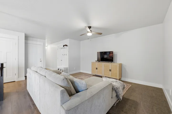 Recessed lighting, wood-finish flooring, built-in mudroom bench with coat hooks, ceiling fan, and white trim