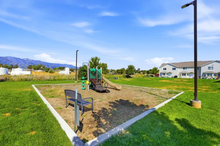 Landscaped common area featuring a playground structure and a metal bench