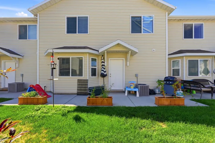 Private concrete patio with direct exterior access, wood planter boxes, and a manicured lawn