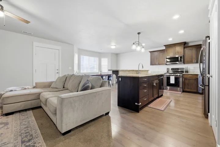 Open-concept kitchen with wood-finish flooring, dark wood cabinetry, and stainless steel appliances