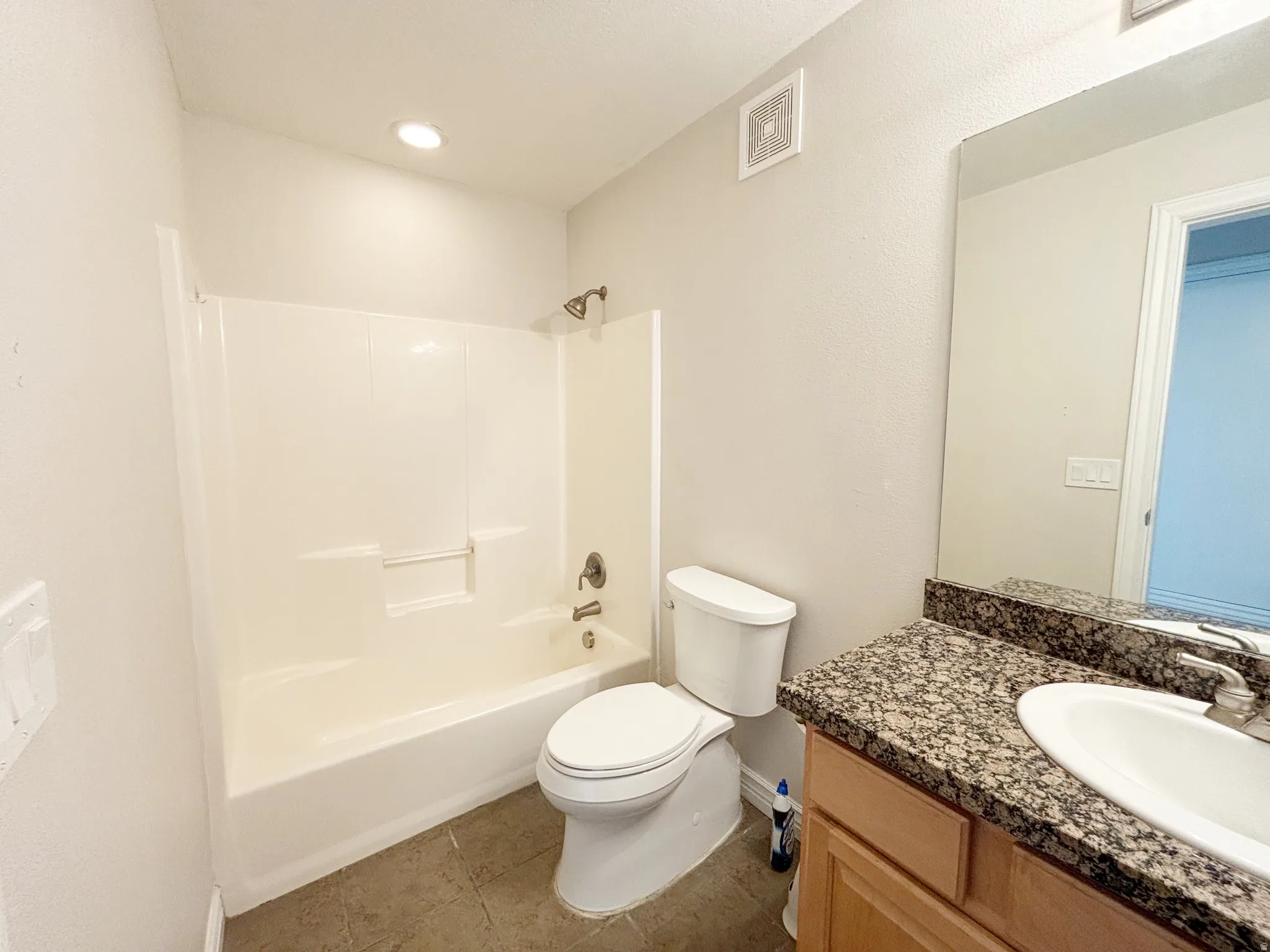 Bathroom featuring a shower-tub combination, a vanity with a granite-style countertop, a rectangular sink, and an expansive wall-mounted mirror