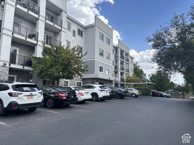 Multi-story building with a light gray facade, dark gray siding accents, and stone-finish lower level