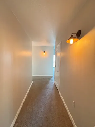 Hallway with neutral wall tones and integrated sconce lighting