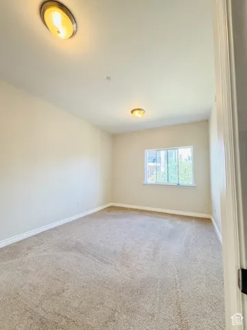Carpeted room with a single window and two ceiling-mounted light fixtures
