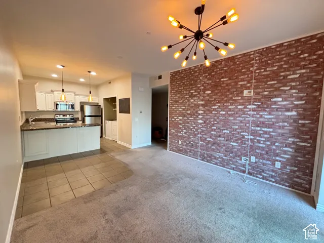 Kitchen featuring white cabinetry, stainless steel appliances, and a breakfast bar with pendant lighting