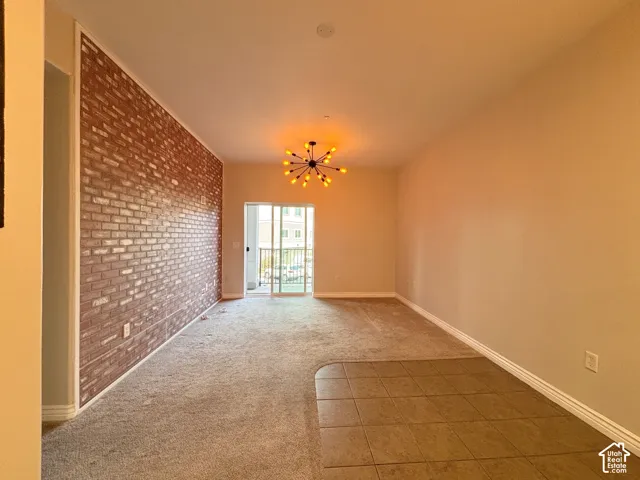 Exposed brick accent wall with a modern sputnik chandelier, carpet flooring, tile flooring, and sliding glass door