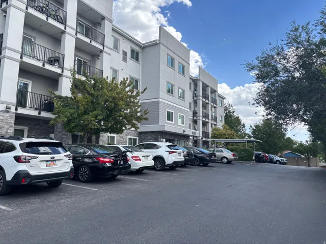 Multi-story building with a light gray facade, dark gray siding accents, and stone-finish lower level