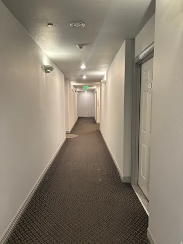 Hallway with patterned carpet flooring, recessed lighting, and wall sconces