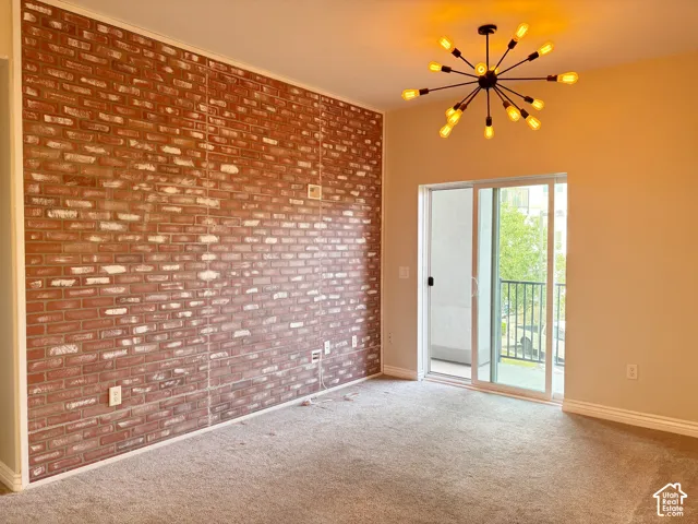 Exposed brick accent wall, modern sputnik chandelier, light neutral-toned walls, sliding glass door, and a private balcony with metal railings