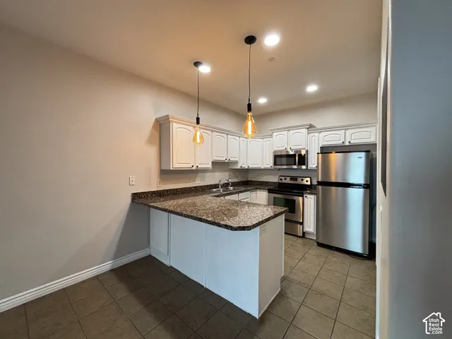 Kitchen featuring white cabinetry, granite-finish countertops, stainless steel appliances, and pendant lighting