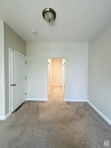 Neutral-toned wall paint, carpeted flooring, white interior door, and ceiling-mounted light fixture