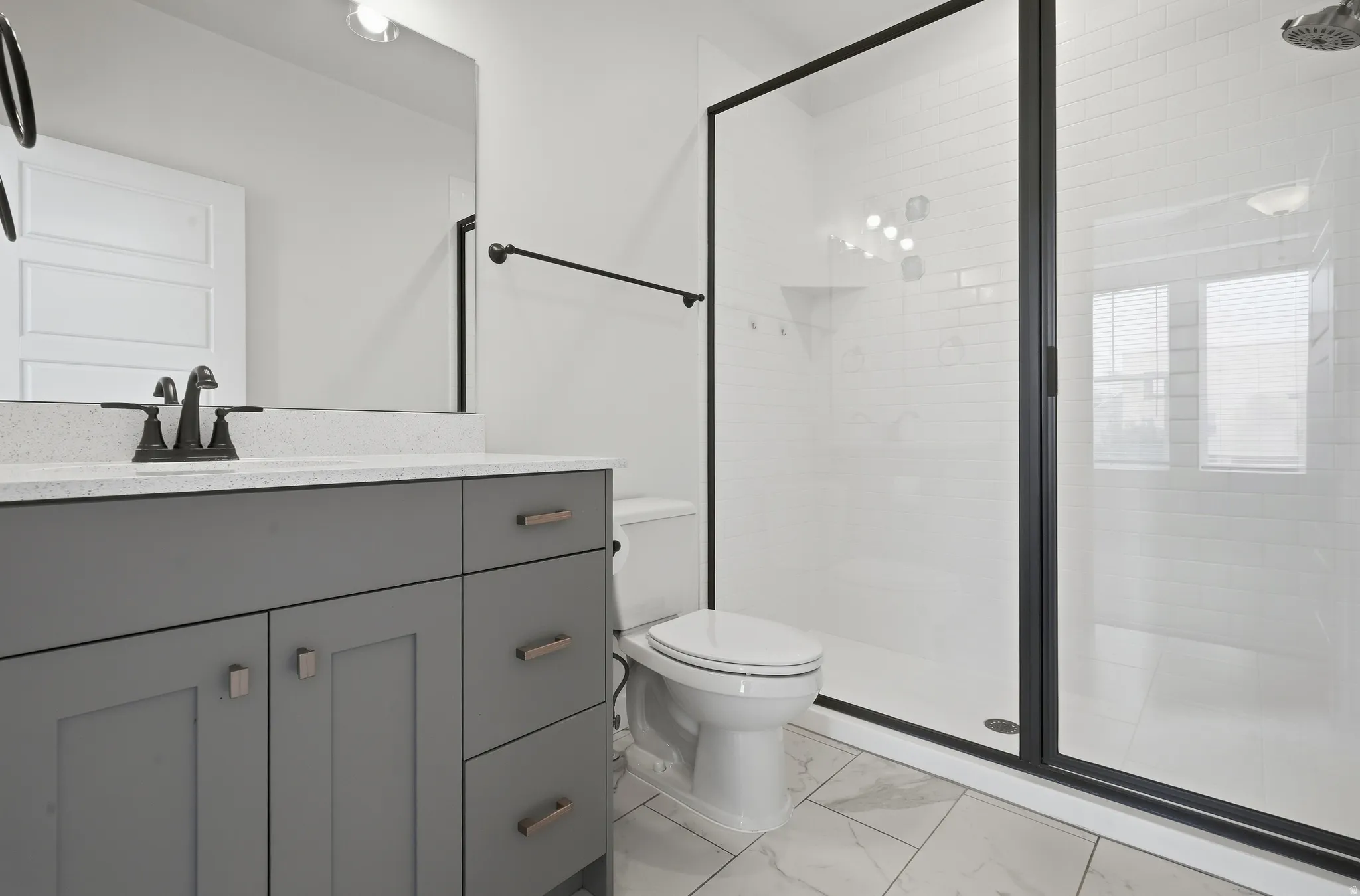 Gray vanity with modern hardware, white speckled countertop, and black faucet