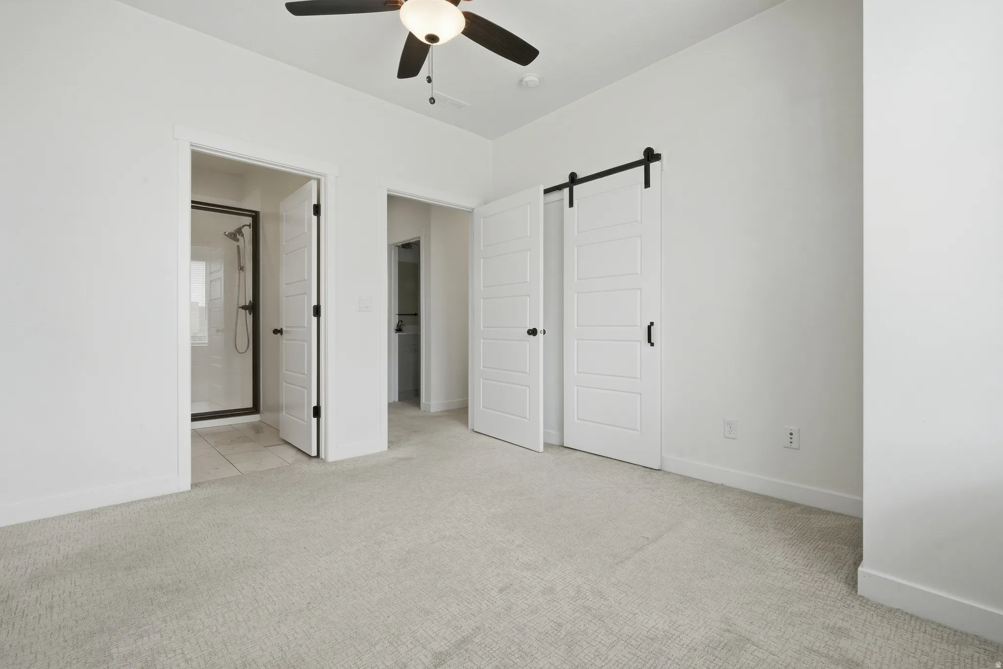 Recessed ceiling lighting, ceiling fan with light fixture, light-toned carpeting, white walls, and a sliding barn door