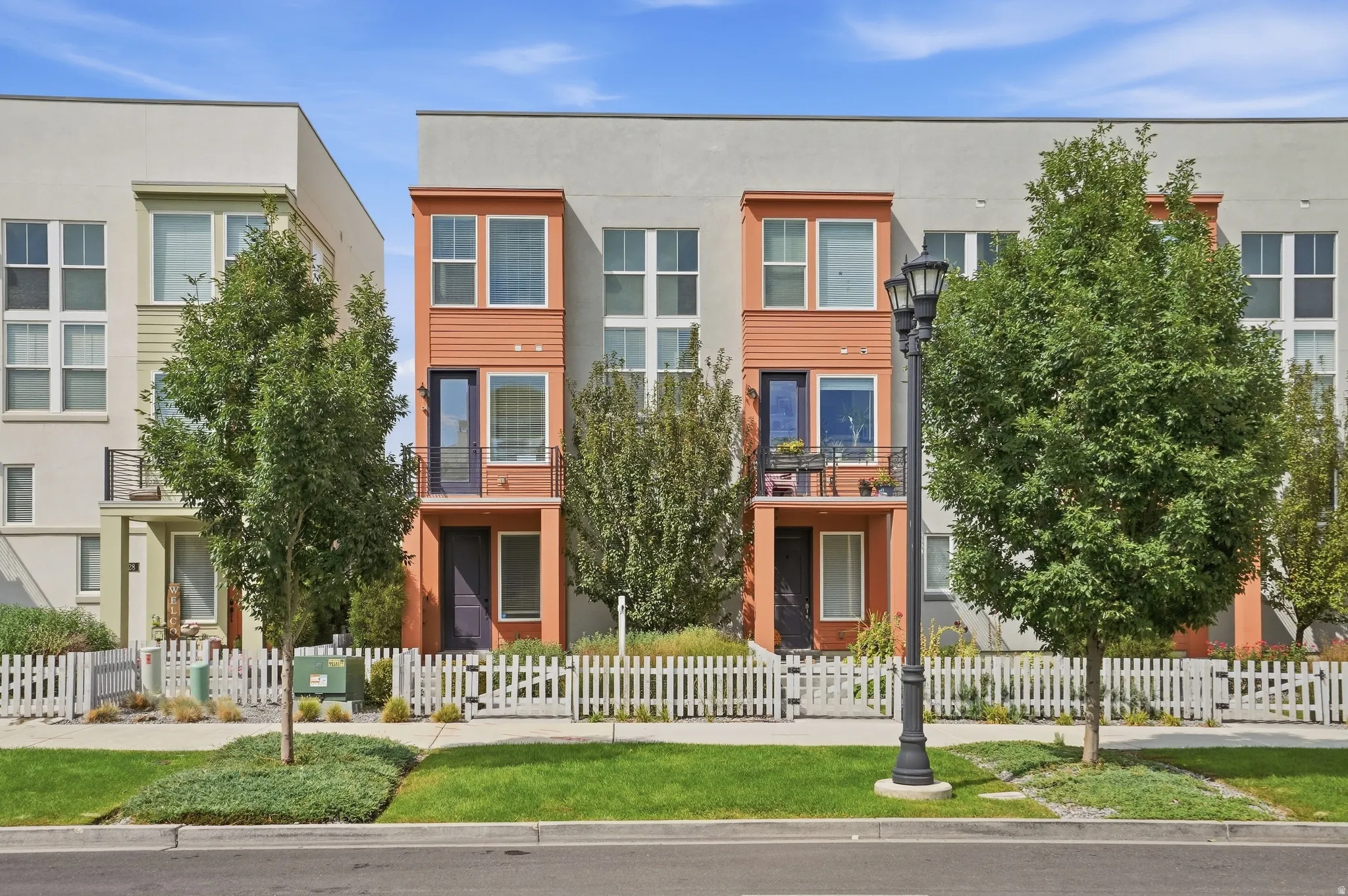 Multi-story exterior with a mix of siding and stucco finishes, featuring a private balcony with iron railing, and a ground-level entrance