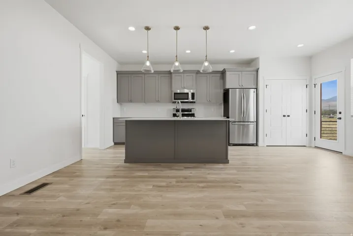 Kitchen featuring grey cabinetry, stainless steel appliances, a central island, and wood-finish flooring