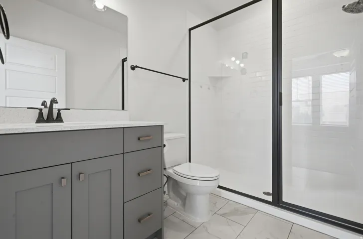 Gray vanity with modern hardware, white speckled countertop, and black faucet