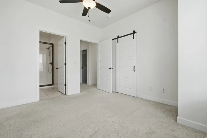 Recessed ceiling lighting, ceiling fan with light fixture, light-toned carpeting, white walls, and a sliding barn door