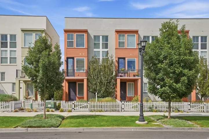 Multi-story exterior with a mix of siding and stucco finishes, featuring a private balcony with iron railing, and a ground-level entrance