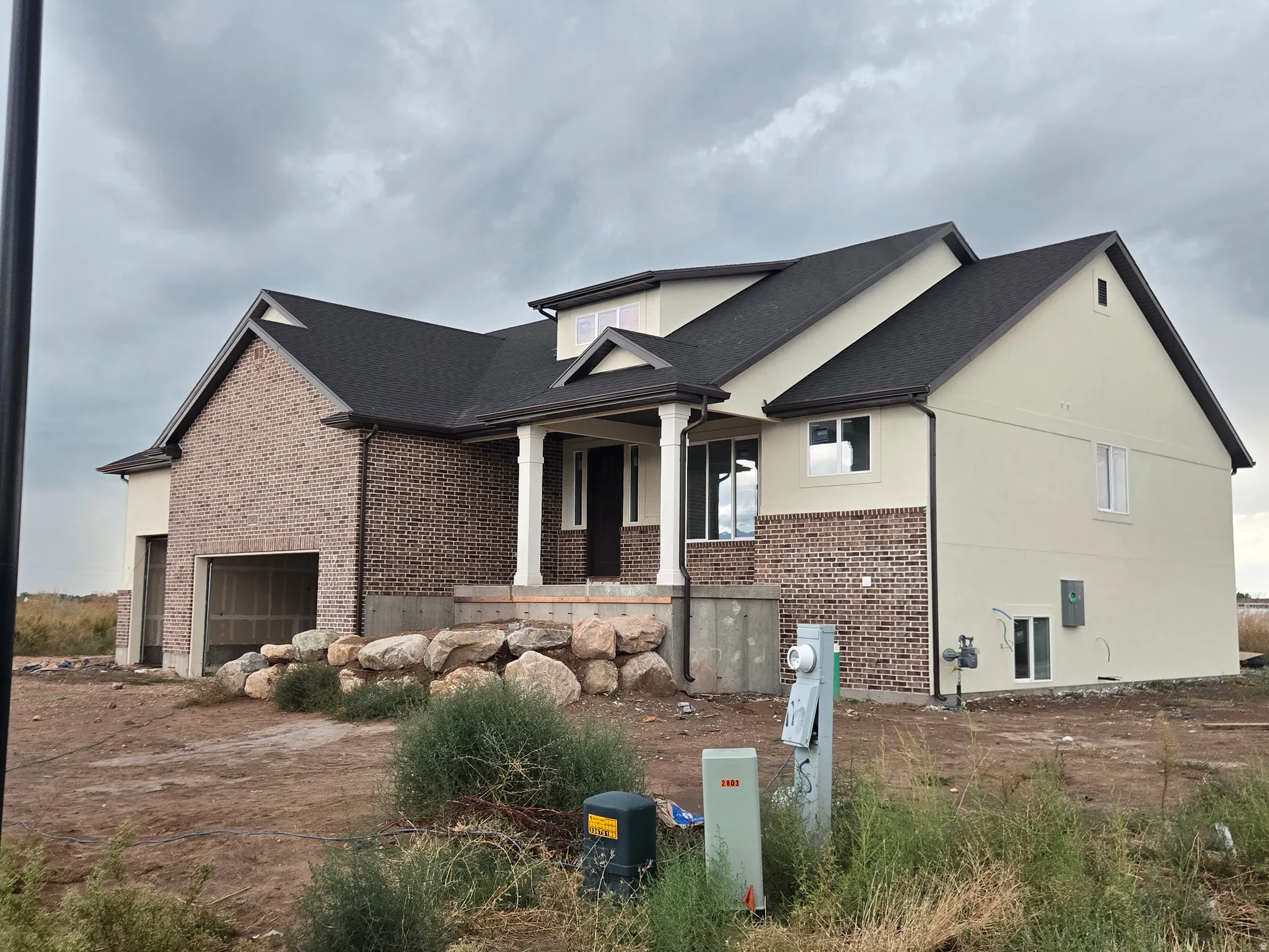 Brick and stucco exterior with a dark shingle roof