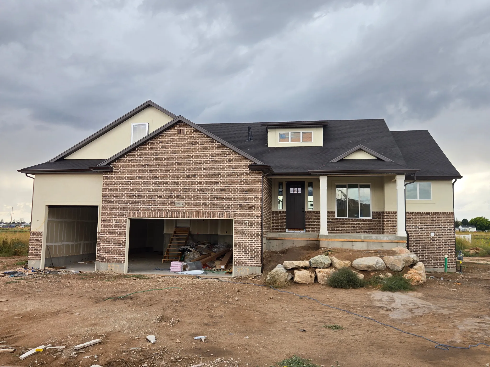 Brick and stucco exterior with a dark shingle roof
