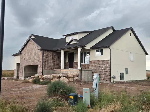 Brick and stucco exterior with a dark shingle roof
