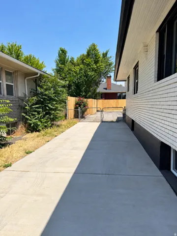 Extended concrete driveway with a chain link gate and wood fencing