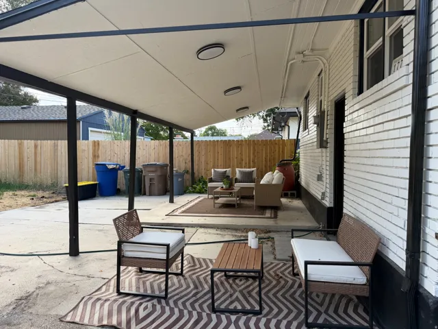 Covered patio with integrated lighting, concrete flooring, and a white brick exterior