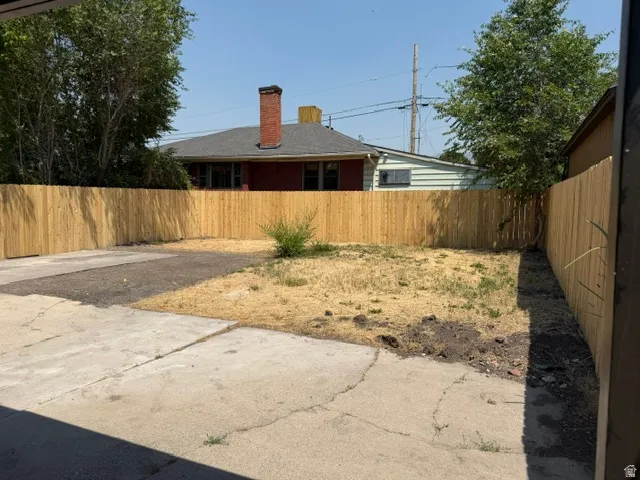 Expansive outdoor space featuring a new wood privacy fence, concrete patio, and a dedicated garden area