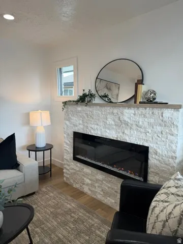 Stacked stone fireplace with a built-in linear electric insert, wood-finish mantel, and recessed lighting
