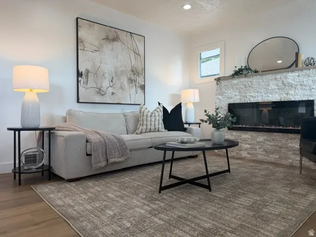 Hardwood-style flooring, recessed lighting, stone-clad fireplace with linear firebox, and a window with white trim