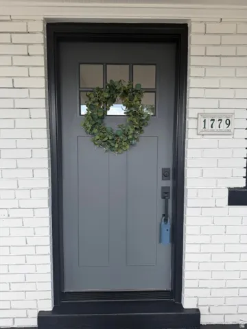Painted brick exterior with a paneled entry door, upper lite window, and dark trim