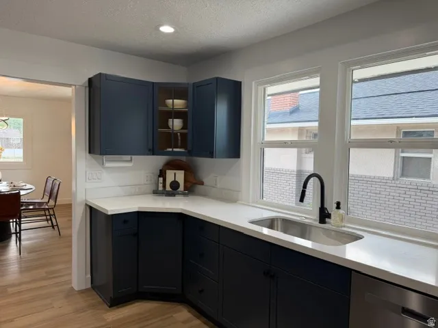 Kitchen featuring dark cabinetry, solid surface countertops, an undermount stainless steel sink, a matte black gooseneck faucet, and recessed lighting
