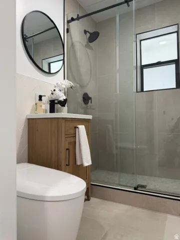 Full bathroom featuring a glass-enclosed shower, wood-finish vanity with a vessel sink, and matte black fixtures