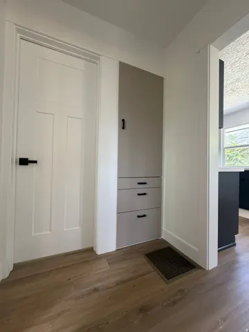 Wood-finish flooring complemented by a white paneled door with black hardware
