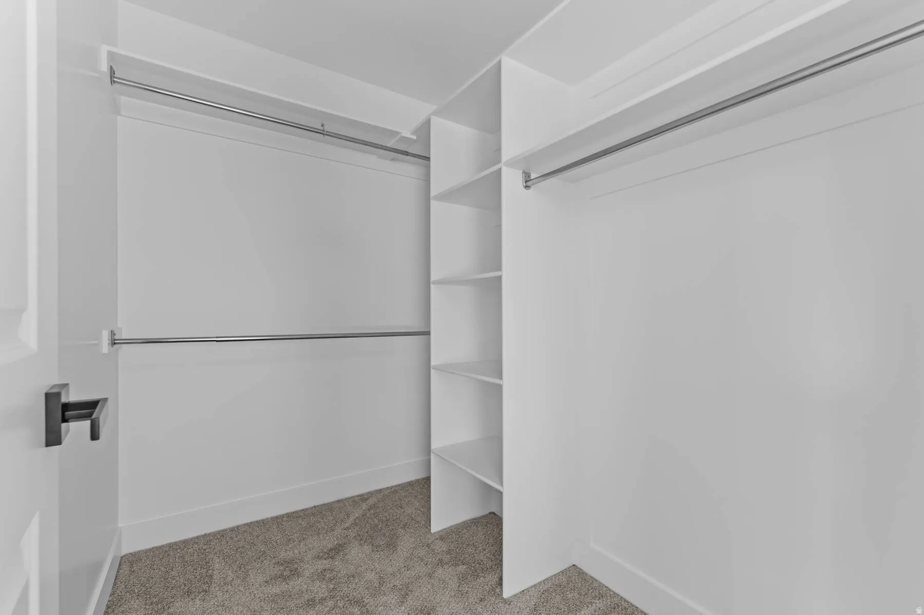 White built-in shelving, chrome hanging rods, and light-toned carpet flooring