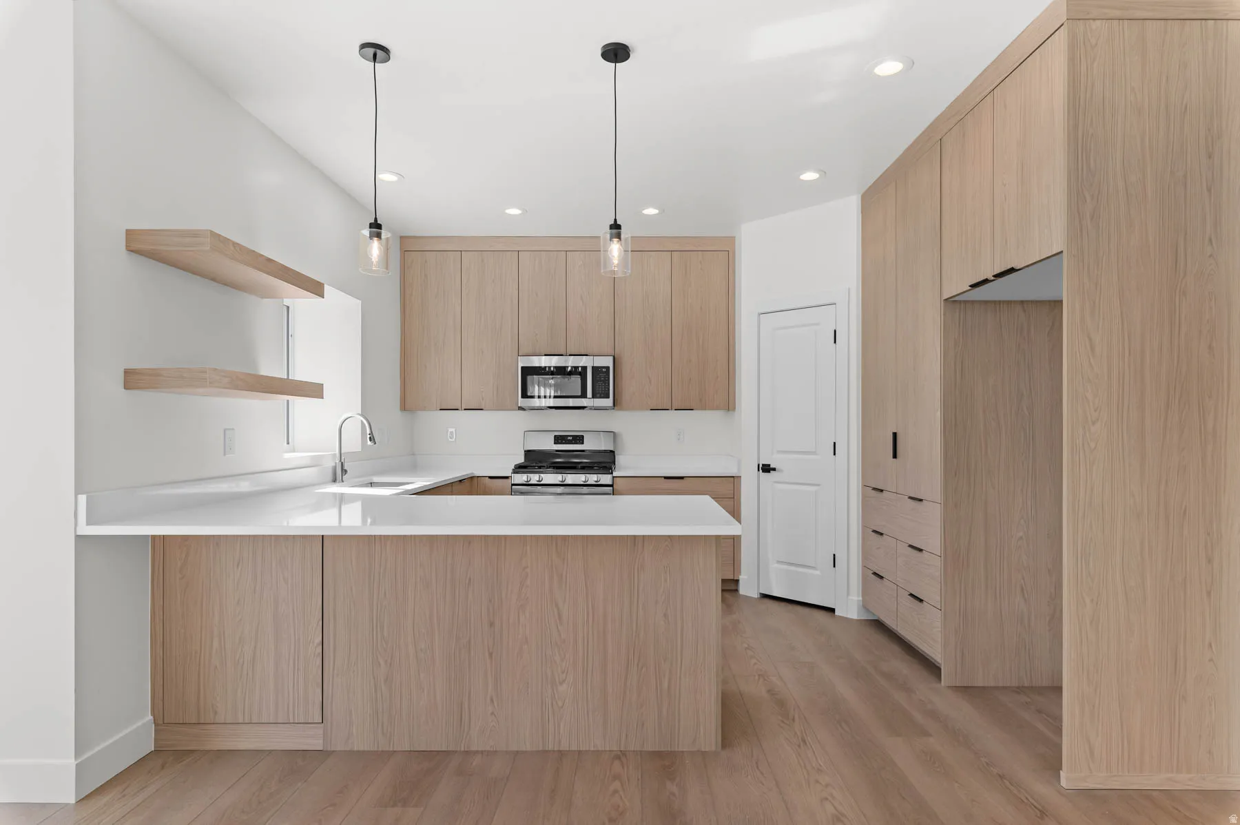 Kitchen featuring wood-finish cabinetry, stainless steel appliances, white countertops, a central island, and wood-finish flooring