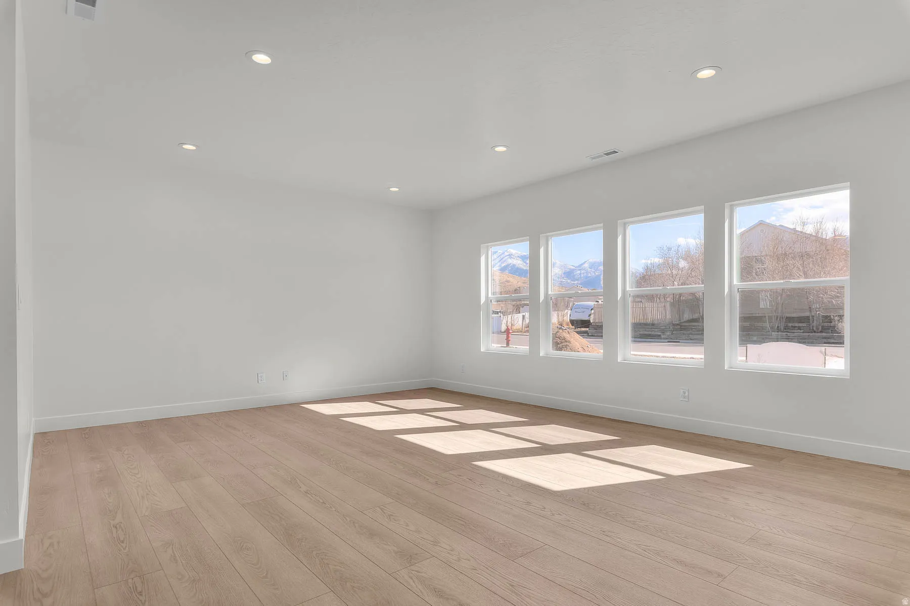 Recessed ceiling lighting, light wood-finish flooring, and multiple large windows