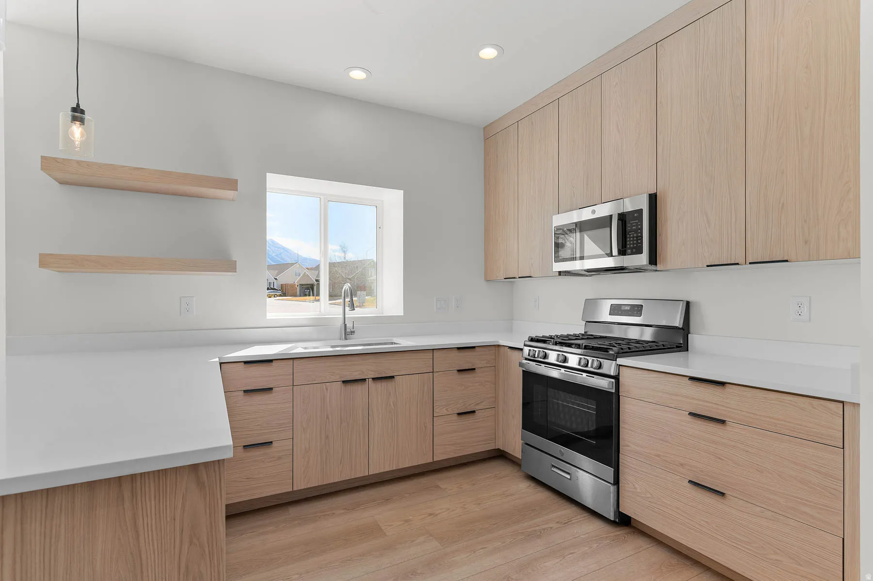 Kitchen featuring wood-finish cabinetry, stainless steel appliances, solid surface countertops, a single basin sink with a gooseneck faucet, and recessed lighting