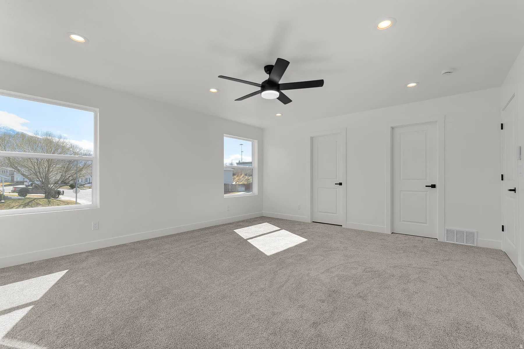 Recessed lighting, ceiling fan with matte black finish, two panel interior doors with matte black hardware, dual windows, and wall-to-wall carpeting