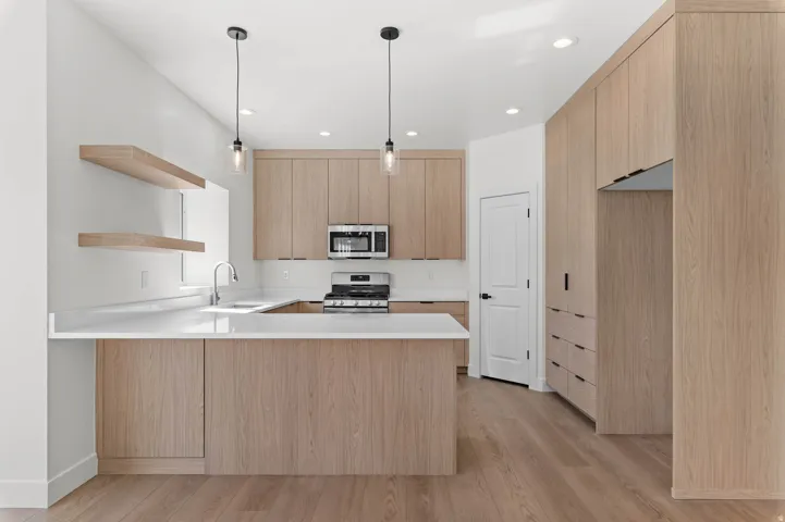 Kitchen featuring wood-finish cabinetry, stainless steel appliances, white countertops, a central island, and wood-finish flooring