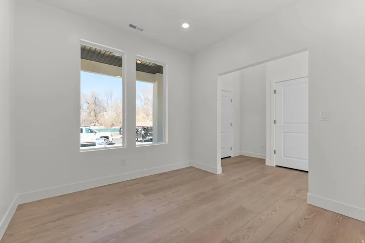 Recessed lighting, wood-finish flooring, white trim, and white paneled interior doors